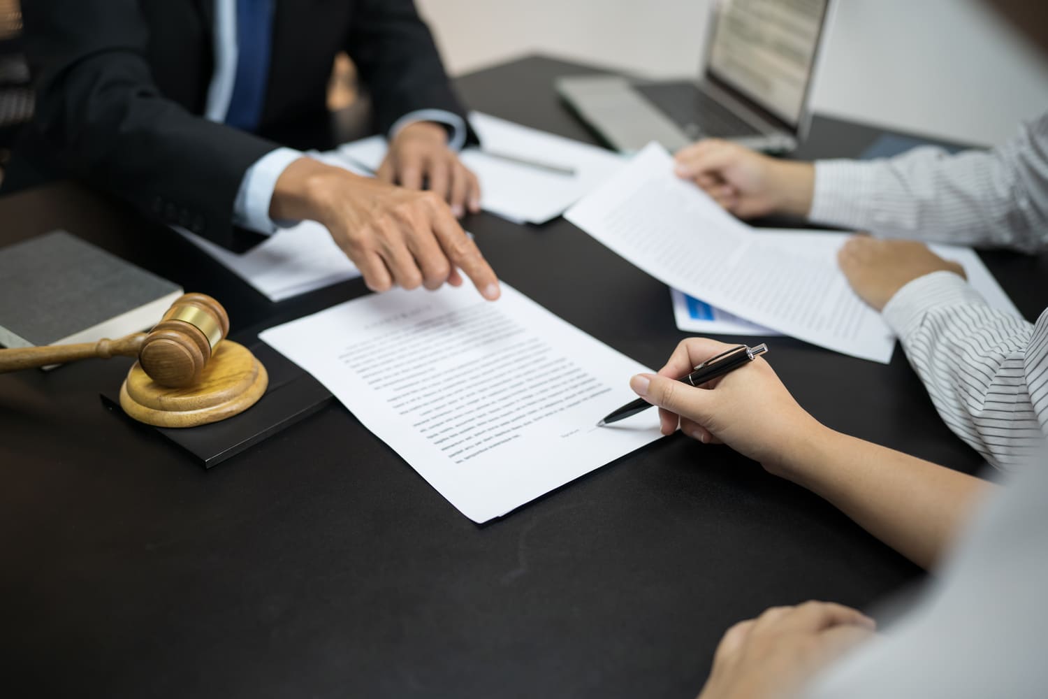 Abogado y cliente revisando y firmando documentos legales en una mesa de oficina.